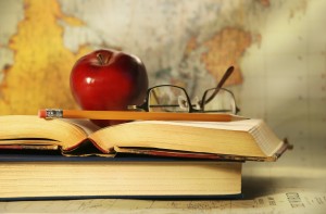 Old books with red apple and glasses on study desk